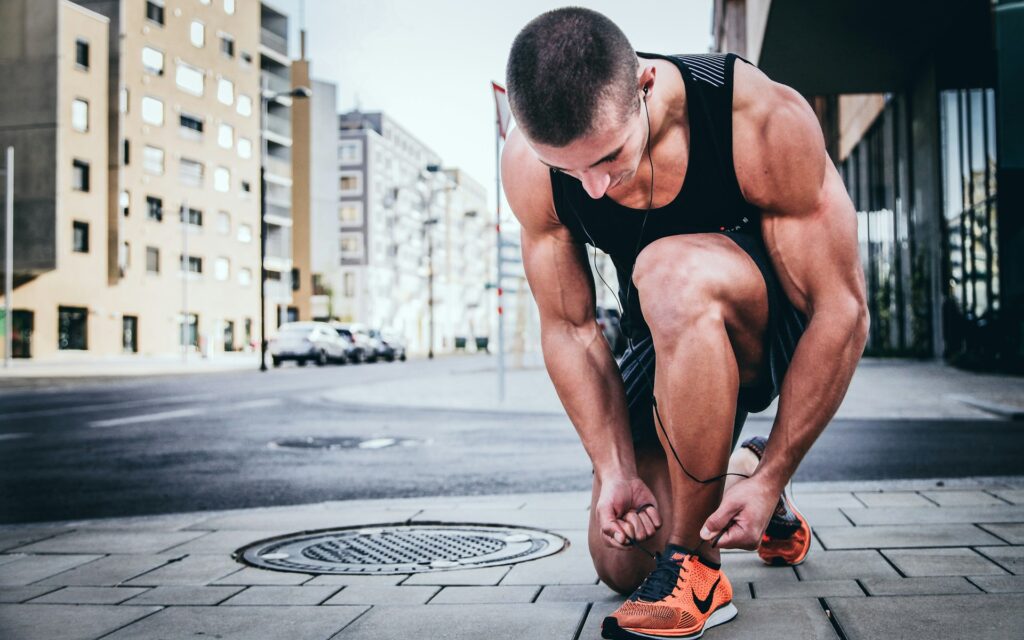 Man lacing her shoes getting ready to run in the street