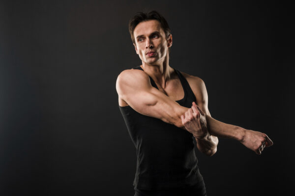 Man stretching his shoulders with a black background