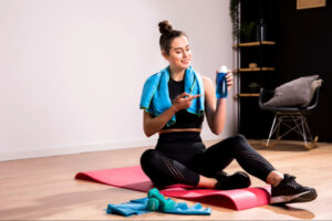 Woman seated post-workout with hydration and recovery essentials, representing lifestyle-based insulin modulation through exercise, movement consistency, and personalized metabolic wellness support.