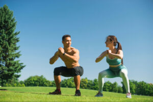 Man and woman performing outdoor squats together, reflecting lifestyle-driven metabolic support, exercise-enhanced appetite regulation, and the synergistic role of physical activity alongside semaglutide’s neurohormonal effects.