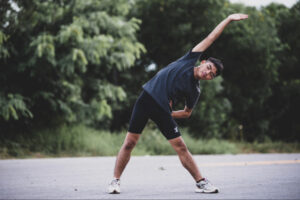 Active man performing outdoor mobility and stretching exercises, representing sustainable fitness habits, personalized wellness routines, and the role of structured lifestyle support in long-term weight management success.